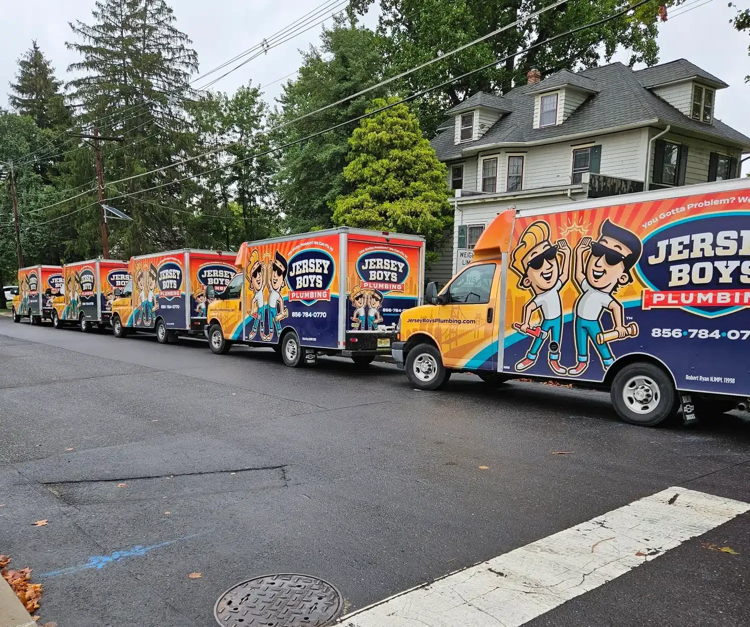 Jersey Boys Plumbing trucks parked on the side of the road on residential street in New Jersey.